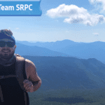 GIS Planner Jackson Rand poses at the top of a mountain for his submitted photo for his "Get to Know Team SRPC" blog feature