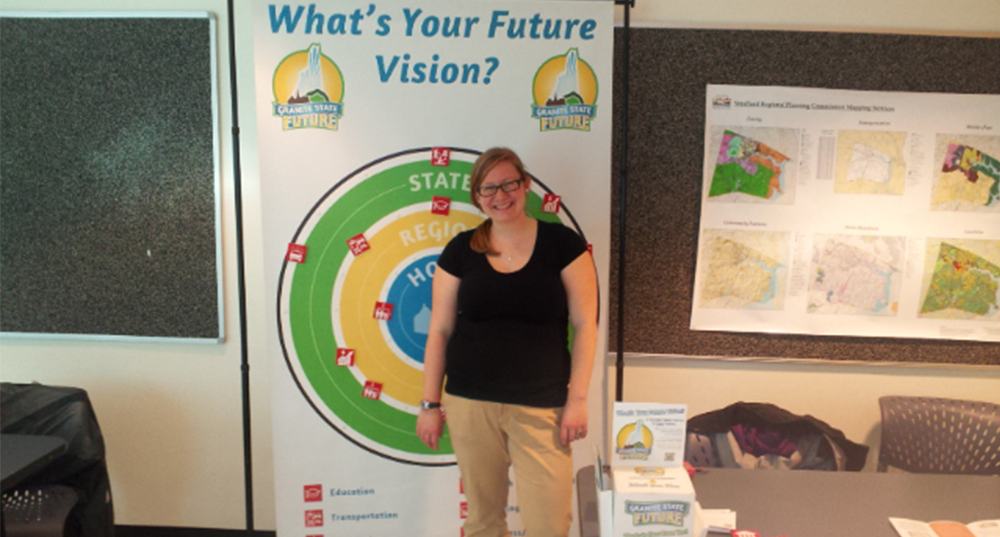 SRPC staffer poses in front of an interactive outreach display assessing regional priorities as a UNH outreach event
