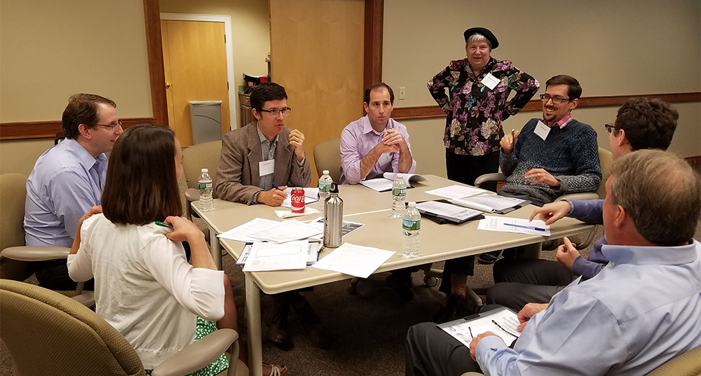 Stakeholders meet around a table as part of the Partnering for Performance NH initiative.