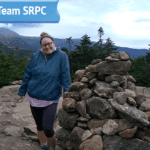 Communications and Outreach Planner Shayna Sylvia poses at the top of a mountain for her submitted photo for her "Get to Know Team SRPC" blog feature