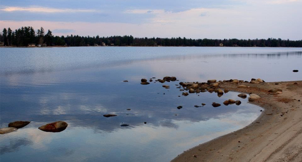 Dusk at Sunrise Lake with a beach in the forefront and treeline in the background